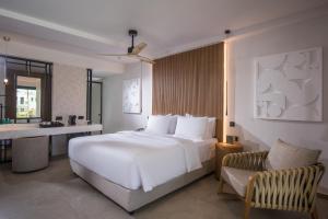 a bedroom with a large white bed and a chair at Noble Hotel & Suites - Adults Only in Gouves +35 photos