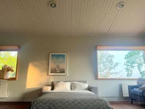 a bedroom with a bed and two windows at Mysigt sommarhus med havsutsikt och bastu in Vaxholm