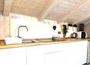una cucina con armadi bianchi e lavandino di Il piccolo Loft nel cuore antico di Aosta - You & Me case vacanza ad Aosta