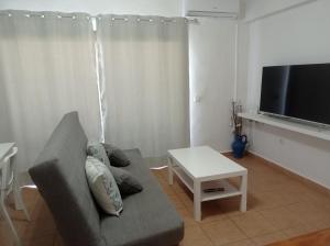 a living room with a couch and a flat screen tv at Apartamento Illa Blanca in Es Pujols