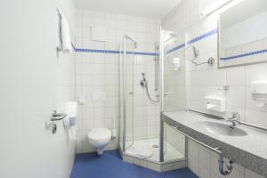 a bathroom with a toilet, sink, and shower at Kurhaushotel Bad Salzhausen in Bad Salzhausen