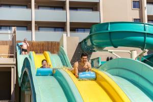 a man riding a roller coaster on a water slide at Jupiter Albufeira Hotel - Family & Fun - All Inclusive in Albufeira
