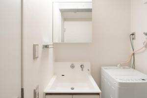 a white bathroom with a sink and a mirror at LUXE Minami Aoyama in Tokyo +27 photos