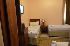 een slaapkamer met 2 bedden en een nachtkastje met een lamp bij Rakhaa Al Deafah Hotel in Mekka