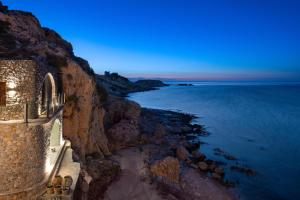 a building on a cliff next to the ocean at Stone Luxury Suites - Adults Only in Archangelos