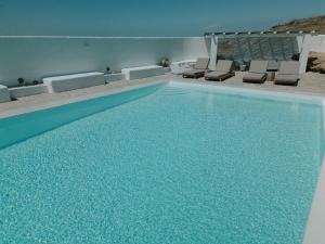 a swimming pool with chairs and a swimming pool at Mykonos Supreme Comfort Suites & Villas in Kalafatis