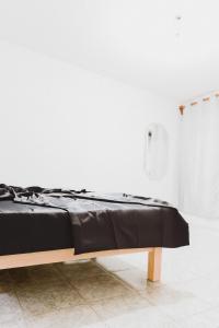 łóżko w białym pokoju z czarnym kocem w obiekcie Casa Oaxaca w mieście Santa María Azompa