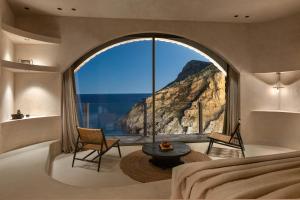- une chambre avec une grande fenêtre offrant une vue sur la montagne dans l'établissement Stone Luxury Suites - Adults Only, à Archangelos