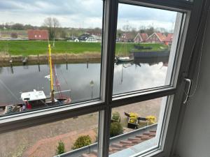 ein Fenster mit Blick auf einen Wasserkörper in der Unterkunft Ferienwohnung am Alten Hafen in Hooksiel