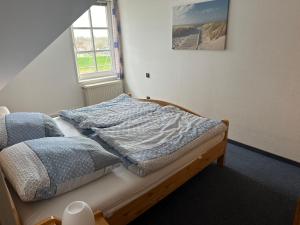 ein unmaskiertes Bett in einem Zimmer mit Fenster in der Unterkunft Ferienwohnung am Alten Hafen in Hooksiel