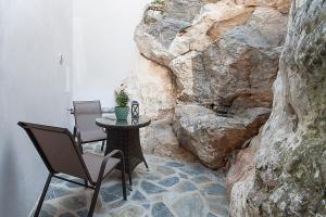 una mesa y sillas en una habitación con una pared de roca en Frina's House Skiathos, en Skiathos