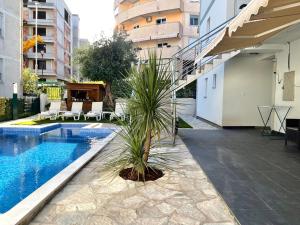 palma siedzi obok basenu w obiekcie Apartments Pribilovic w Budvie