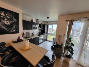 a kitchen with a wooden table and black chairs at Cosy carré Haussmann, stade de franc, C D G, Paris in Le Blanc-Mesnil