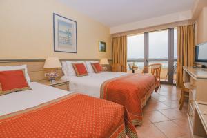 una camera d'albergo con due letti e una televisione di Divani Corfu Palace a Città di Corfù