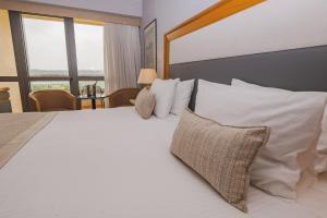 een slaapkamer met een groot bed met witte kussens bij Divani Corfu Palace in Corfu-stad