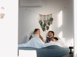 Ein Mann und eine Frau, die im Bett liegen und Bücher lesen in der Unterkunft Grassmere Orchard in Napier