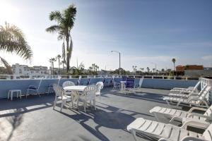 een rij witte tafels en stoelen op een dak bij Newport Channel Inn in Newport Beach