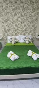 a green bed with towels on it with a wall at Vesuvius Dream in Boscotrecase