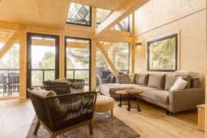 a living room with a couch and chairs and windows at Naturchalets Turracher Höhe by ALPS RESORTS in Turracher Hohe
