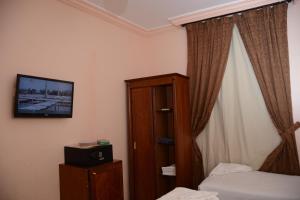 een slaapkamer met een bed en een tv aan de muur bij Rakhaa Al Deafah Hotel in Mekka