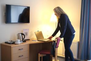 a woman standing in front of a desk with a laptop at Hotel & Restaurant am Schlosspark in Dahme +13 photos