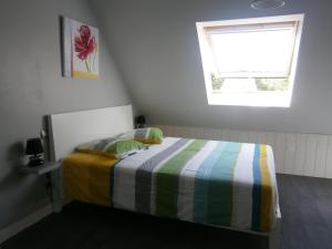 a small bedroom with a bed with a window at Un P'tit Coin De Paradis in Santec