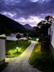 a gravel road with a house and mountains in the background at Camping White Rock in Castellane