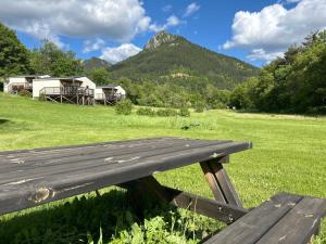 a wooden bench sitting in a field with a mountain at Camping White Rock in Castellane
