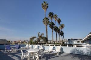 een patio met tafels en stoelen en palmbomen bij Newport Channel Inn in Newport Beach