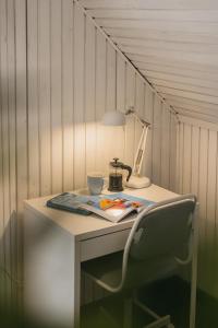 einen Schreibtisch mit einem Stuhl, einer Lampe und einer Tasse in der Unterkunft Guboja in Nida