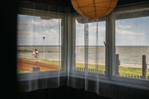 ein Fenster mit Blick auf das Meer und eine Person auf einem Motorrad in der Unterkunft Guboja in Nida