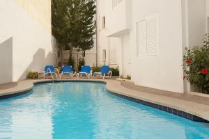 a swimming pool with blue chairs and a building at Apartment Voltor 2 C By SunVillas Mallorca in Pollença