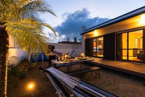 ein Haus mit einer Terrasse mit einem Tisch und einer Palme in der Unterkunft 広い庭でプールとバーベキューが楽しめる!和室とキッズスペース付き! in Ōdo