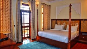 a bedroom with a bed and a large window at Devnadi Hotel in Haridwār