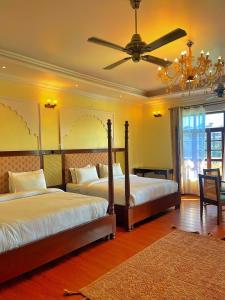 a bedroom with two beds and a ceiling fan at Devnadi Hotel in Haridwār