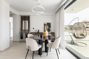 a dining room with a black table and white chairs at Black Lotus Pool Villa, Afitos #FeelsLikeHome in Afitos +19 photos