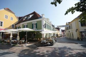 une rue avec des tables et des parasols devant un bâtiment dans l'établissement Gasthof Restaurant Zum Brauhaus, à Hartberg