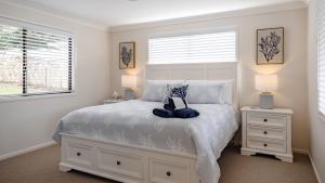 a bedroom with a white bed and two windows at Sandy Cottage in Narrawallee