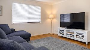 a living room with a couch and a flat screen tv at Sandy Cottage in Narrawallee