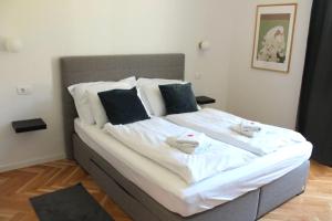 uma cama com lençóis brancos e duas toalhas em Zest and Nest Boutique Apartments em Zagreb