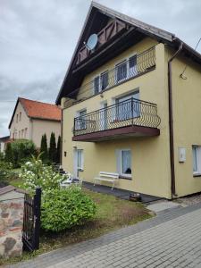 żółty budynek z balkonem i ławką w obiekcie Pokoje i Apartamenty u Anny w mieście Mikołajki