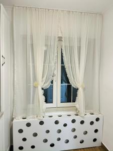 1 dormitorio con cortinas blancas y ventana en Dream Rooms, en Hunedoara