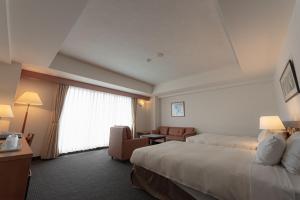 um quarto de hotel com uma cama e uma sala de estar em Hotel Atollemerald Miyakojima em Ilhas Miyako