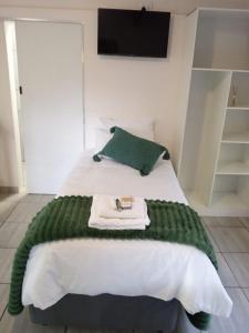a green blanket on a bed with a tv on the wall at Cozy Corner in Groblersdal