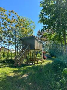 a smallshed in a field with trees in the background at CAMPING ONLYCAMP VAUBAN in Neuf-Brisach
