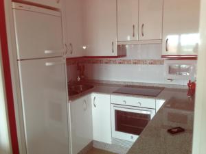 a white kitchen with white cabinets and a sink at Apartamento en A Revolta, Sanxenxo in Sanxenxo
