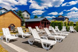 a row of white lounge chairs on a patio at Willa Alexandria - Domki, Apartamenty, Pokoje z Basenem in Karwia