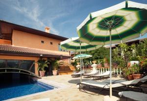 - une terrasse avec des chaises et un parasol à côté de la piscine dans l'établissement Villa Dallas Residence, à Varna