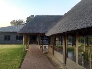 a building with a thatched roof and a walkway at Vista ORT in Kempton Park