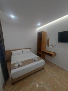 a bedroom with a bed and a tv on the wall at Piazza Apartments in Velipojë